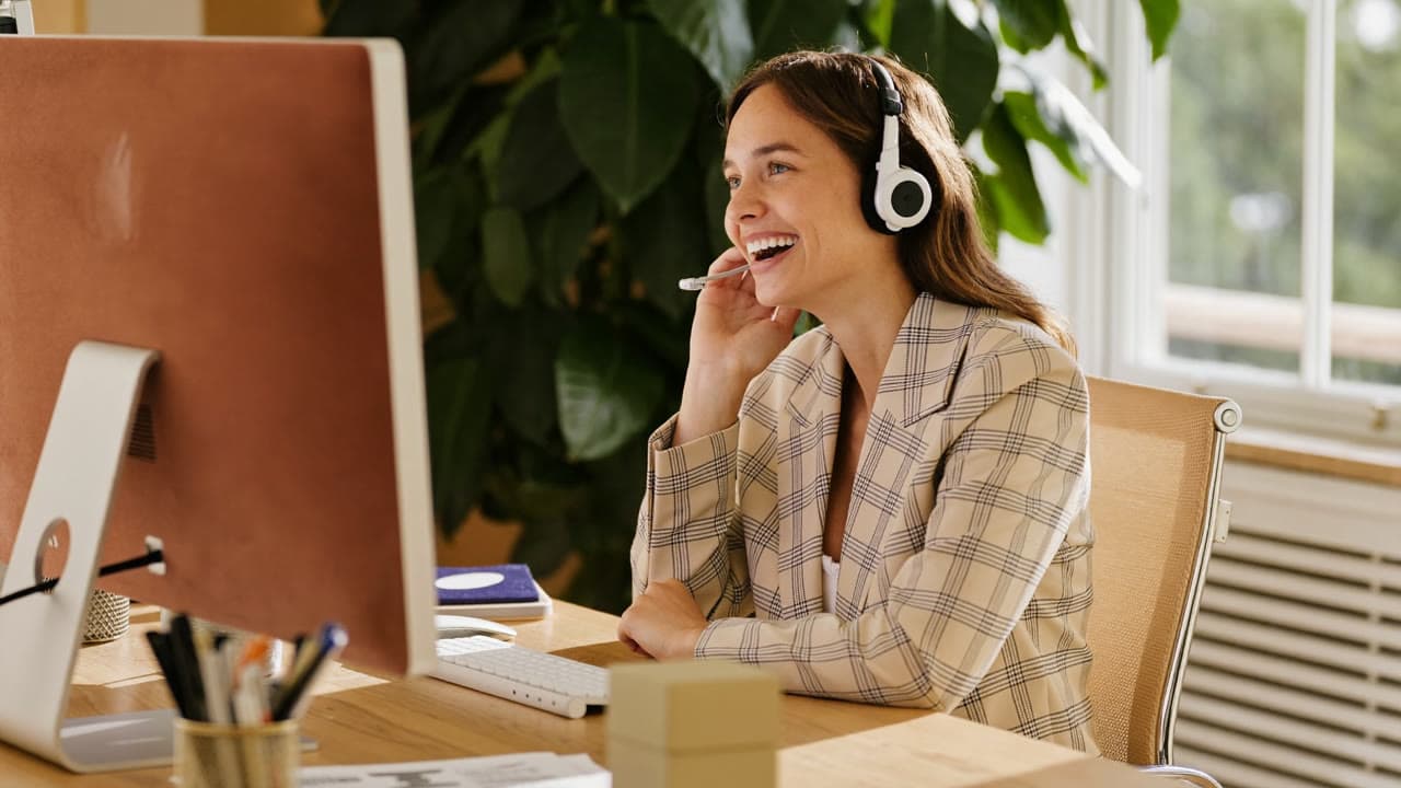 Freundliche Mitarbeiterin mit Headset nimmt einen Anruf entgegen
